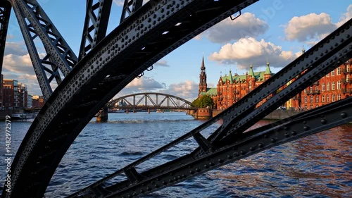 In Hamburg's Speicherstadt, an arch bridge spans the canals, illuminated by warm evening sunlight on a red brick building