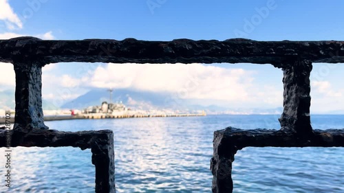 Slow Motion Ocean Waves and Distant Lighthouse Framed by Pier Railing. Moody Coastal Scene