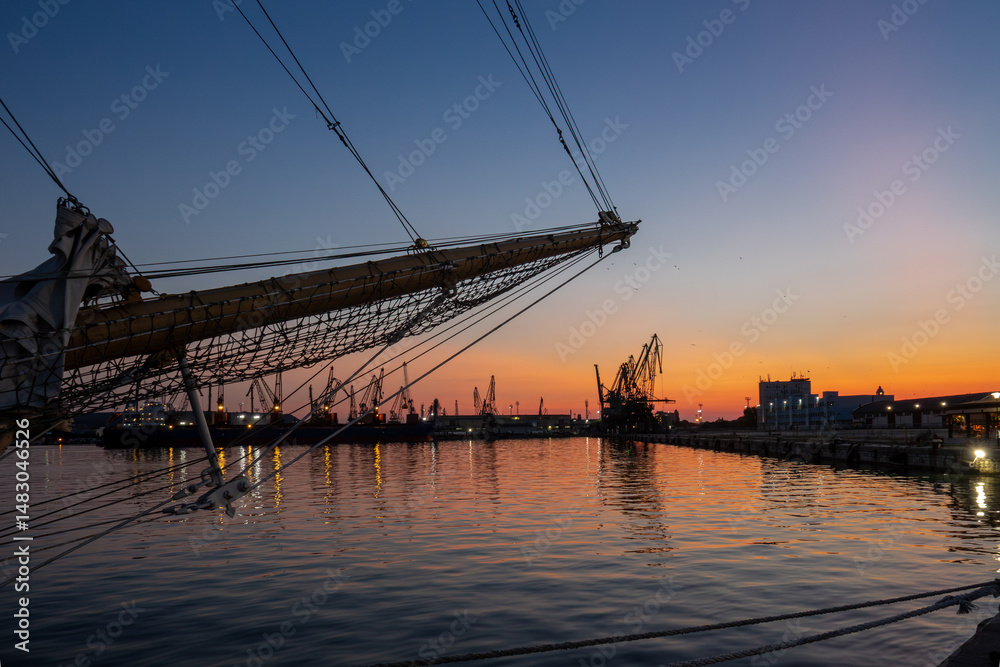 Fototapeta premium Tall ship silhouette in harbor at sunset. Scenic maritime evening view, travel destination.
