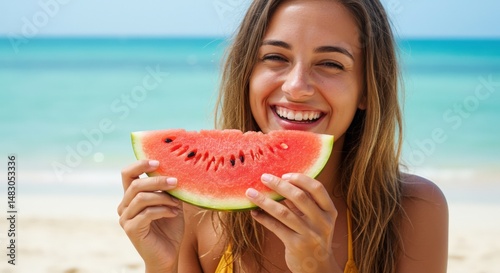 Young woman joyfully holding a slice of watermelon on a sunny beach with ocean waves in background photo
