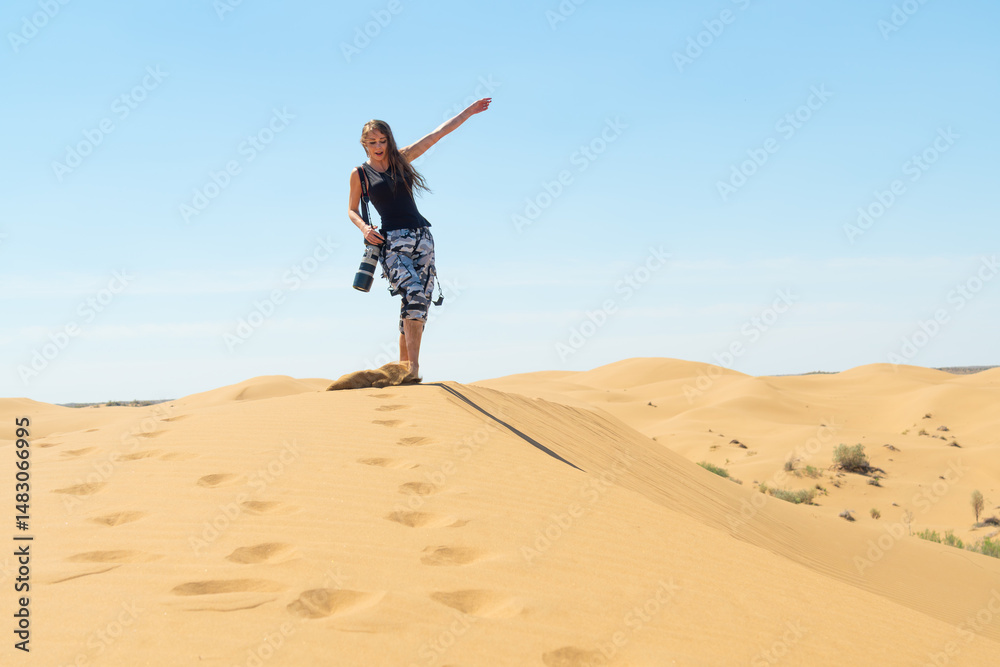 Photographer walking on top of a dune in Kyzylkum Desert with camera in hand Photographer walking on top of a dune in Kyzylkum Desert with camera in hand