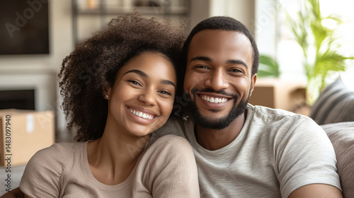 Happy couple embracing in their new home, smiling warmly. Boxes and plant in the background, cozy atmosphere.
