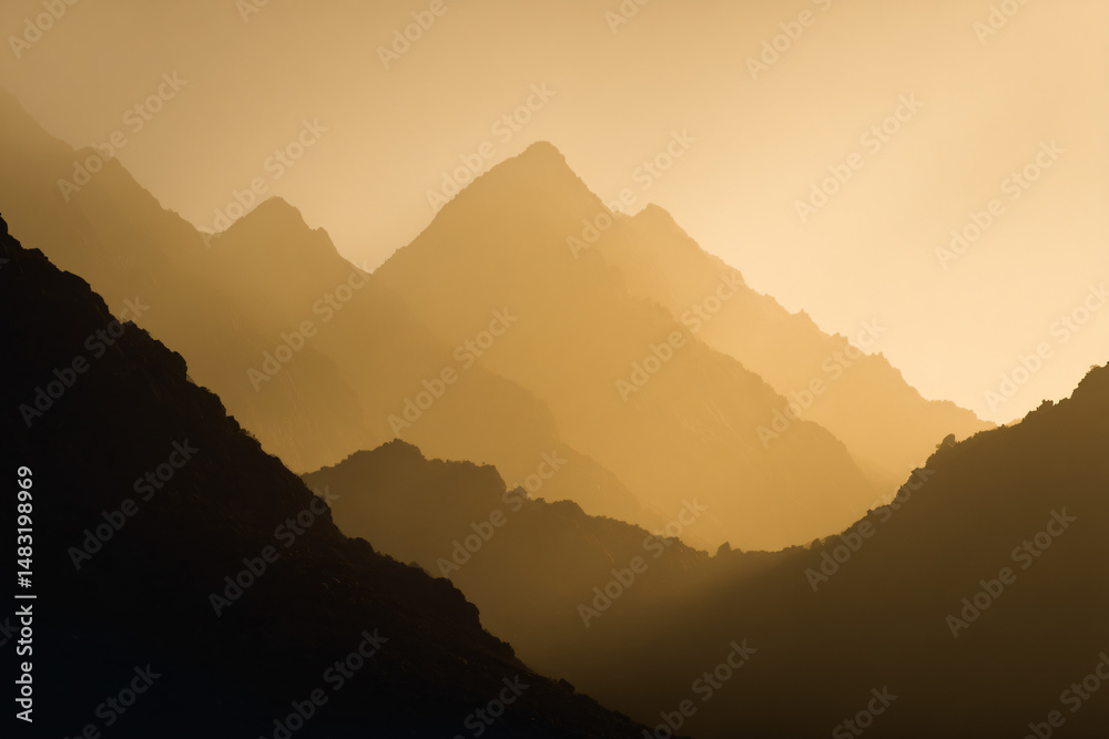 Obraz premium 015-049-Clouds-073-_distant_mountain_range_silhouetted_by_golden_li