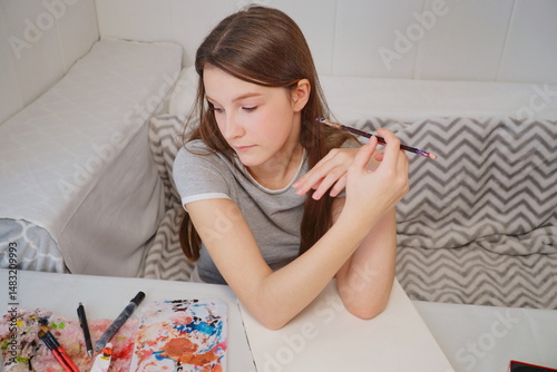 shot of a little girl painting with acrylics and imagining an idea at the table