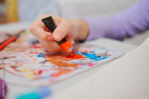 Close-up of a little girl hand squeezing paint to start painting