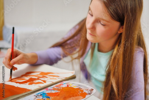 Close-up of a little girl mixing paints with a brush on a palette