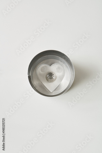 Metal heart-shaped cookie cutter resting on a white surface, ideal for baking and craft activities at home