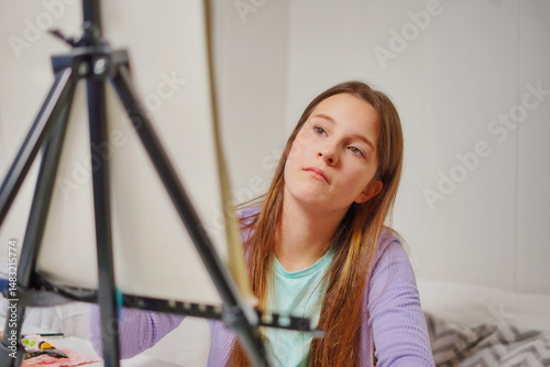 Close-up of a little girl with long brown hair sitting at a desk with an easel