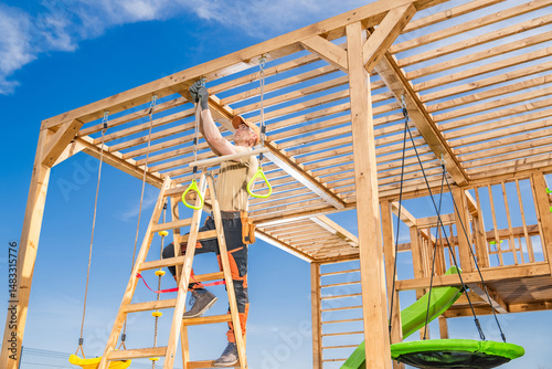 Φωτογραφία Construction Worker Builds Children's Playground Structure on a Sunny Day With C