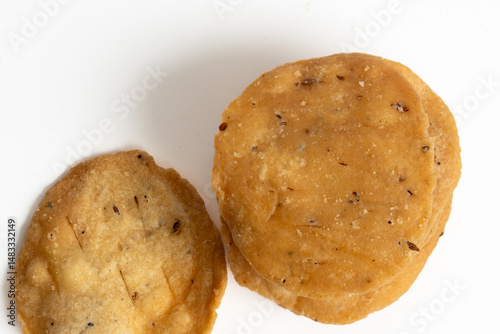 Stack of mathri, or Mathi an Indian a flaky biscuit savoury snack made with all-purpose flour, wheat  flour on white backgropund. Top view.