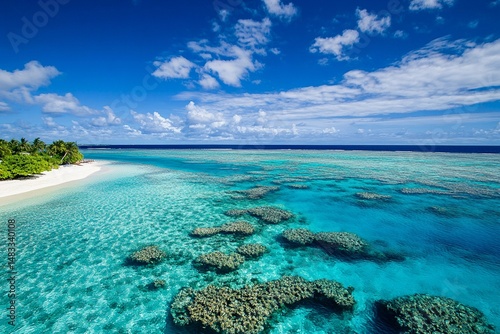 Clear turquoise waters display vibrant coral formations alongside a pristine white sandy beach under a bright blue sky in a tropical paradise location