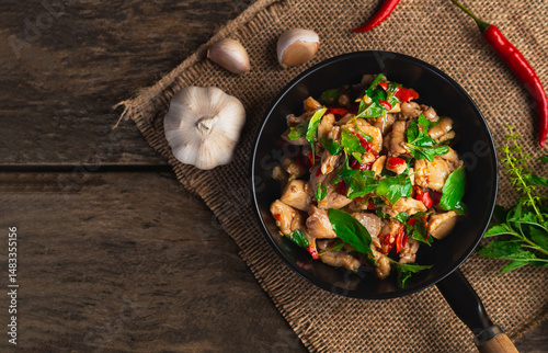Top view of stir fried chicken with basil and chili in mini pan on wooden background. Thai Food