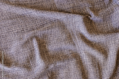 Close-up of gray, beige and white textured fabric. Intricate weave pattern and subtle folds create a rich visual effect.