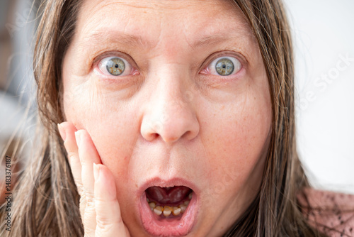 Amazed woman stares in shock, eyes wide open, bulging eyes, expressing disbelief and unexpected news, human emotion