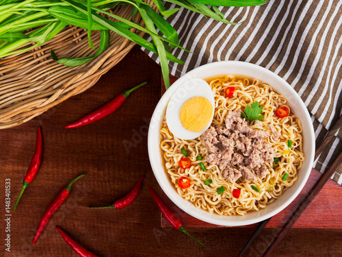 Top view of instant noodle soup with minced pork and half boiled egg in white bowl on wooden table background. Asia Food