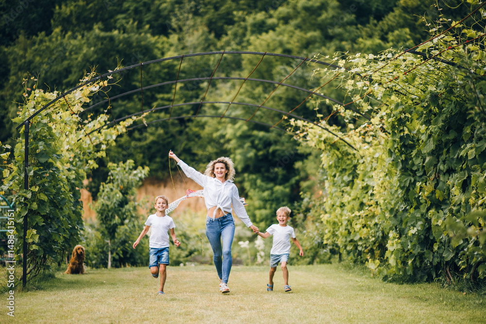 Obraz premium Mother and sons flying a kite. Happy Family day. Family flying a kite in a clearing near the forest.