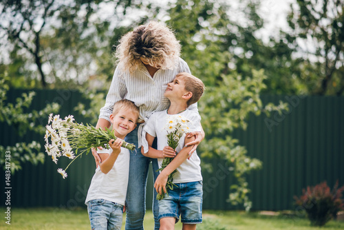 Two sons give their mother a bouquet of flowers. Mother's Day. Mom received a bouquet of flowers as a Mother's Day gift.