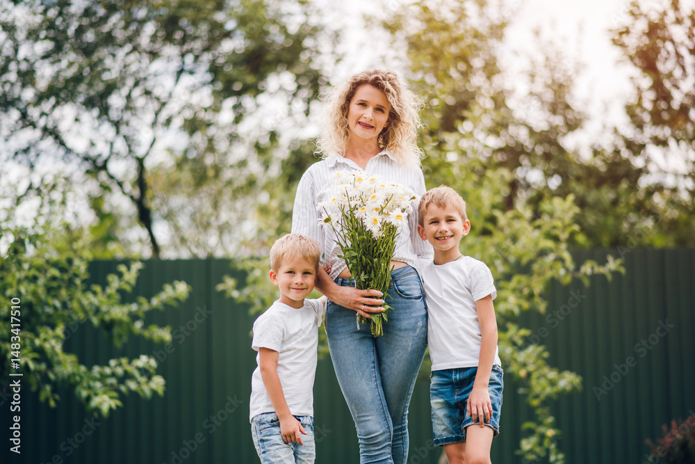 Fototapeta premium Two sons give their mother a bouquet of flowers. Mother's Day. Mom received a bouquet of flowers as a Mother's Day gift.
