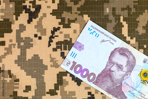 Ukrainian hryvnia on the background of pixel camouflage uniforms of the Ukrainian army. War in Ukraine photo
