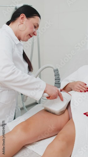 Cosmetologist doctor makes a woman cavitation LPG vacuum roller massage on legs. Correction figures in spa salon clinic. Improving body shape anti-cellulite. Weight loss, lymph drainage. Vertical shot