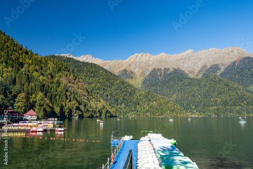 Gaga district, Abkhazia October 12, 2024: Lake Ritsa is located high in the Caucasus Mountains. Boats sail along the smooth turquoise water, the occasional boat cuts through. The mountains around are 