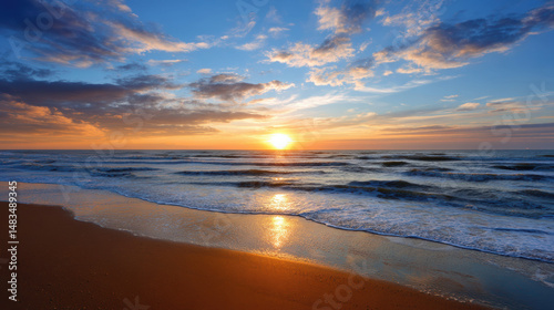 Golden sunlight glistens over gentle waves lapping against a serene sandy beach under a vibrant blue sky filled with picturesque clouds at sunset.