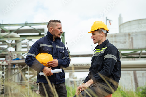 Engineer workers discussing work outdoor at oil refinery factory. Gas petroleum industry transport pipeline deploy building