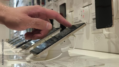 Smartphones store. Customer choosing a new mobile phone in a shop. Showcase with selling various new smartphones in electronics store during a sale