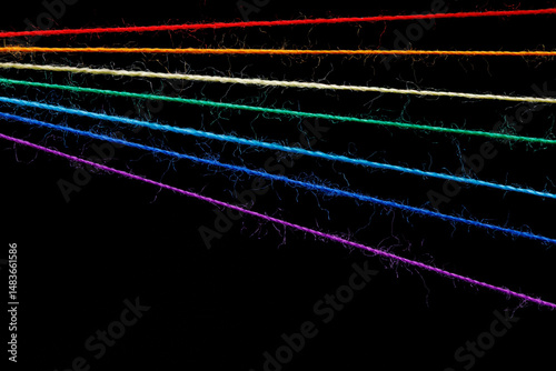 multicolored sewing threads in the form of a rainbow on a black background
