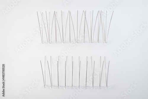 Bird deterrent spikes arranged in rows with varied prong density on clear plastic bases. Perfect for bird control system manufacturers, maintenance professionals, home security installers