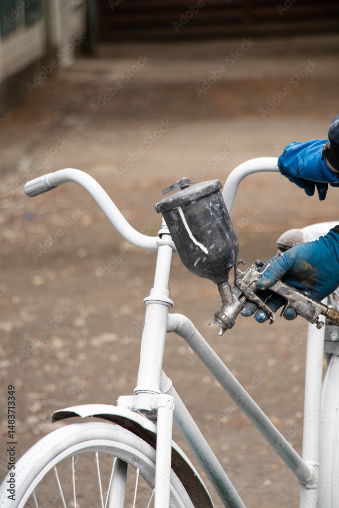 Obraz premium Painting an old bicycle with an airbrush outdoors in white, bicycle restoration