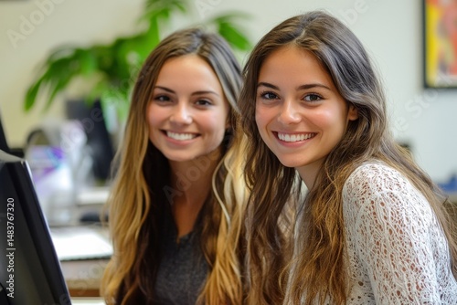Two beautiful business women working together on computer in the office