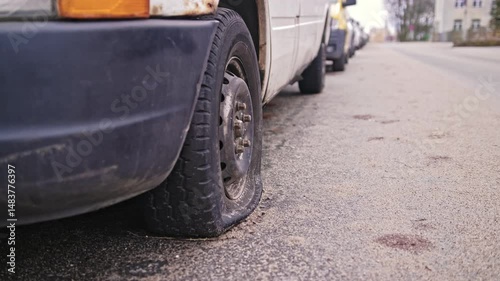 Car with Flat Tyre Parked by Street Curb