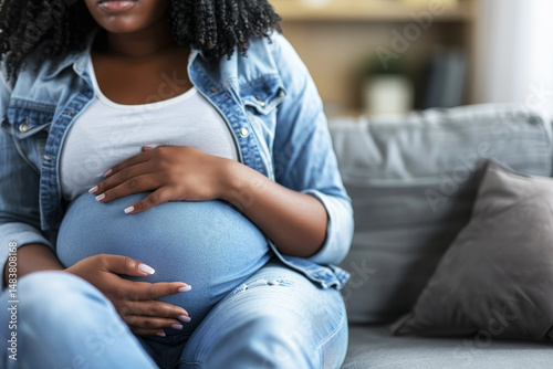 Close up of expecting mother   s hands gently cradling her baby bump with soft blur