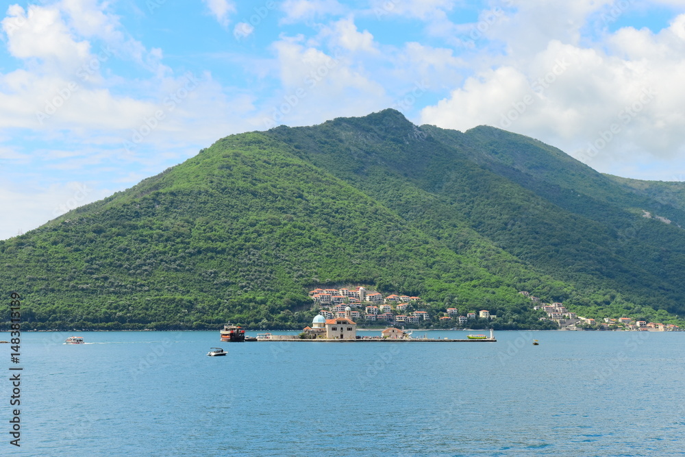 Fototapeta premium PERAST, MONTENEGRO - MAY 06 2024: Tourists are relaxing on the sea and walking on the street, on May 06, 2024 in Perast, Montenegro. During spring on a sunny day.