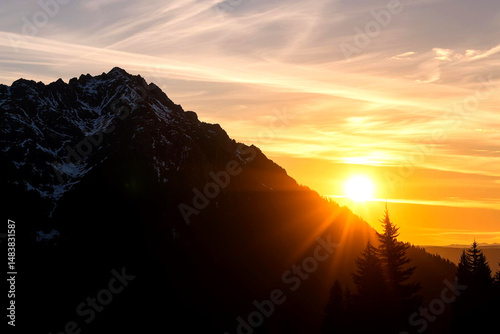 Majestic mountain silhouette against vibrant orange sunset sky with snow-capped peaks