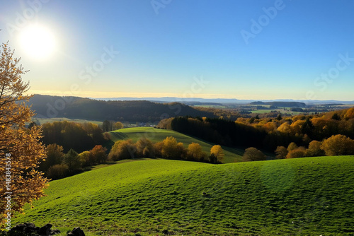 Serene Rolling Hills and Forests Under a Radiant Sunny Sky at Dawn or Dusk