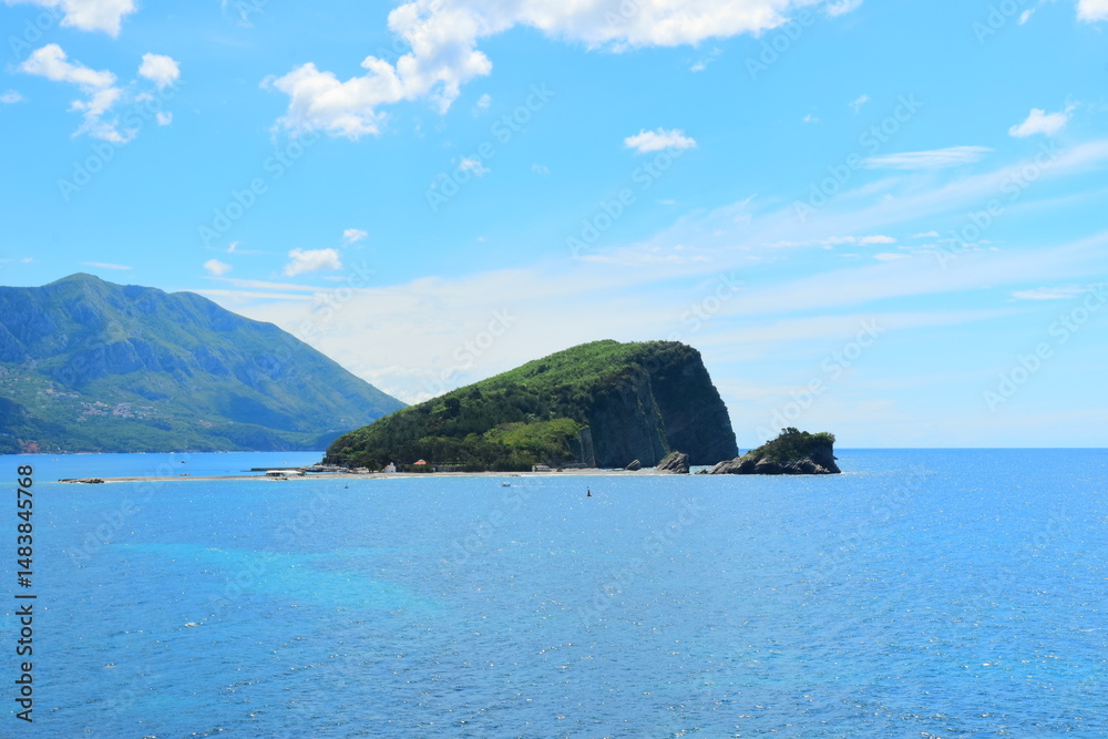 Fototapeta premium Budva, Montenegro - May 04, 2024 : The Old Town Fortress in Budva. A stone wall on the shore of the Adriatic Sea in Montenegro. Horizontal. On a hot, sunny, spring afternoon. 