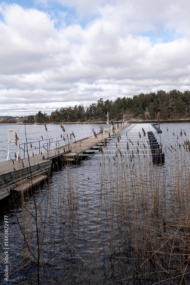Obraz premium Empty marina for tourist and boating season to start. Early spring view of mooring. landscape with row of free piers on lake. Sunny cloudy day.