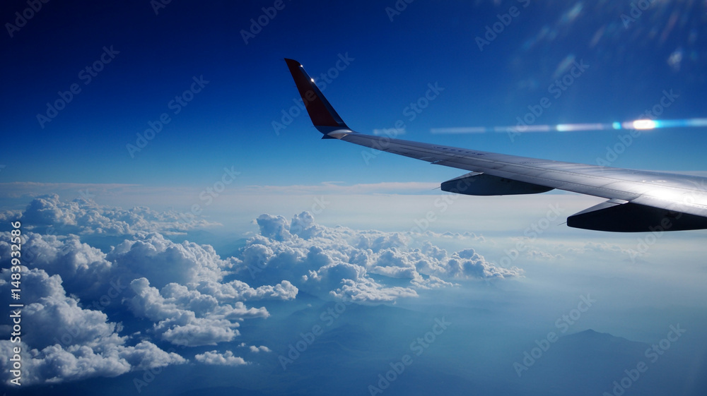 Aerial view of an airplane wing above a sea of clouds in a deep blue sky Aerial view of an airplane wing above a sea of clouds in a deep blue sky