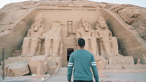 A young man walking towards the temple of nefertari next to the temple of Abu Simbel in southern Egypt next to Lake Nasser. Temple of Pharaoh Ramses II, 4k video