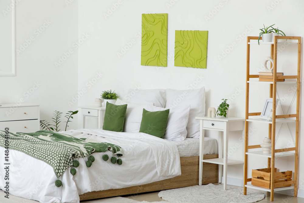 Obraz premium Interior of stylish bedroom with cozy bed, bedside table and beautiful paintings
