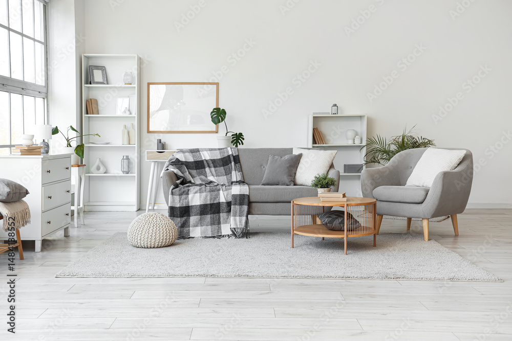 Obraz premium Interior of light living room with grey sofa, armchair and table
