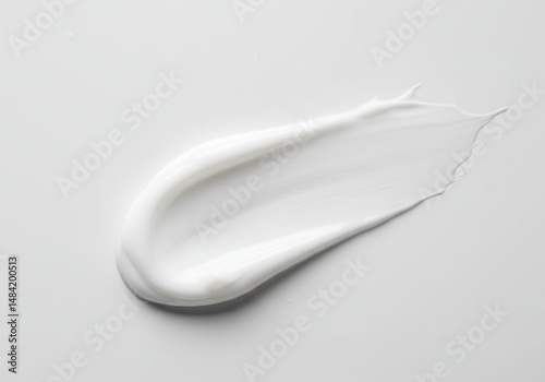 White cream smear on a gray background, showcasing smooth texture and light reflection