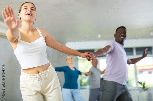 фотографія Young woman coach rehearsing with group of multinational sports aged people soci