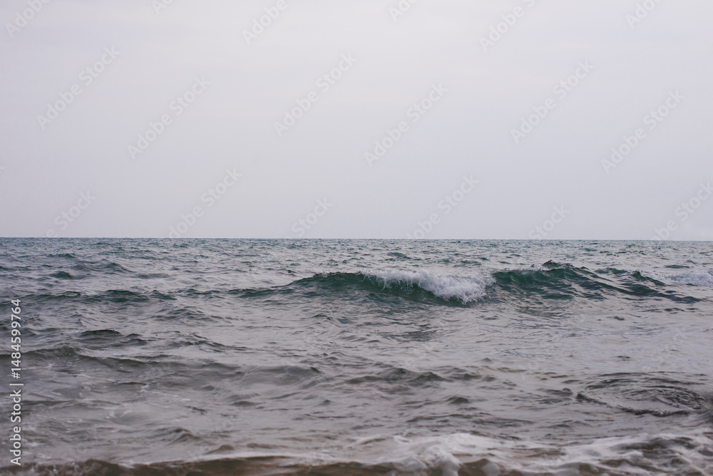 Fototapeta premium Waves of the sea on a cloudy day. Selective focus.