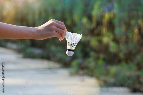 Hand holding a shuttlecock, concept for outdoor badminton playing in free times, soft and selective focus.