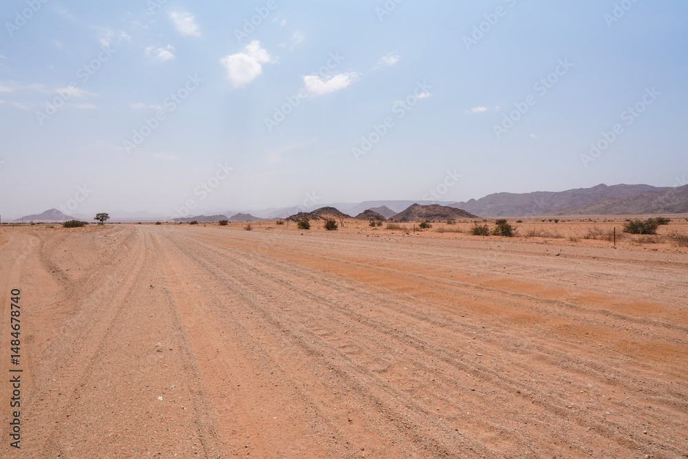 Obraz premium Sandpiste als Strasse quer durch die weiten Wüsten von Namibia im Namib Gebiet