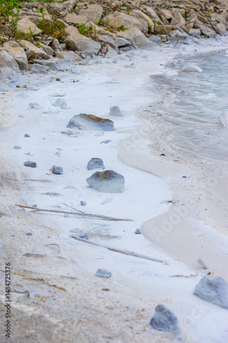 Azure waters of Quarry Lake meet white mineral deposits creating a dramatic natural shoreline. Calcium-rich sediment forms distinctive pale formations along the rocky edges of the former mining site