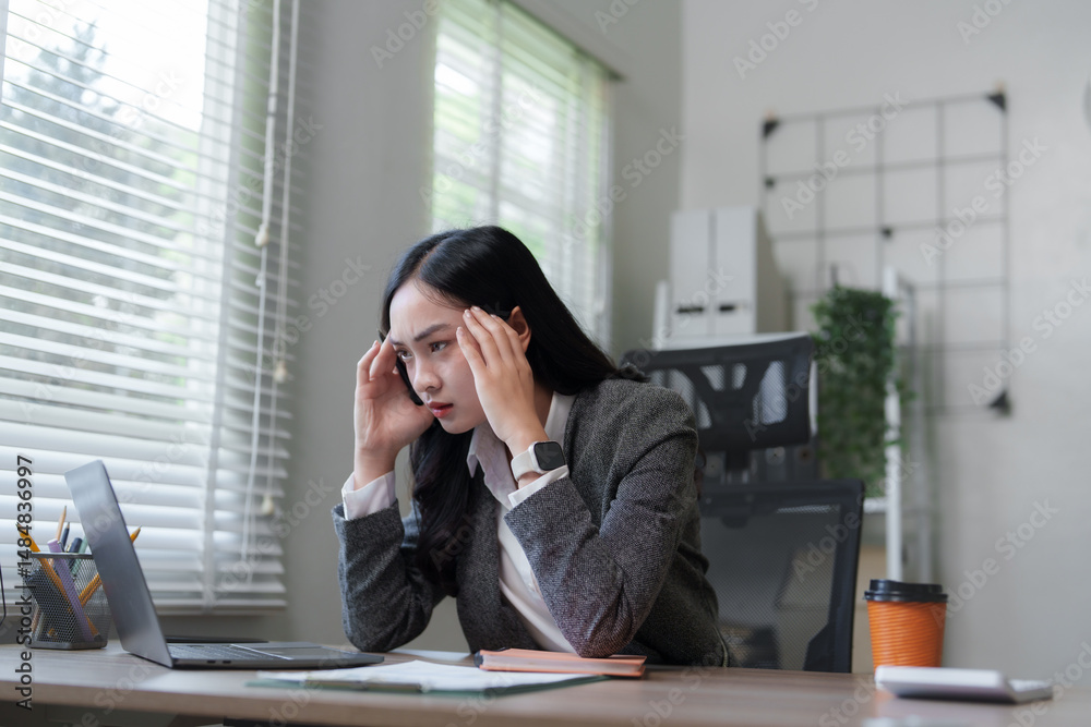 Stressed asian businesswoman having headache while working on laptop in office Stressed asian businesswoman having headache while working on laptop in office